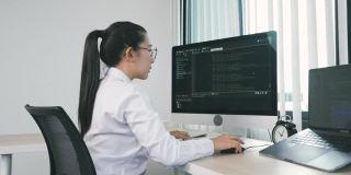 亚洲女性软件开发人员正在分析写进办公室电脑程序的代码。