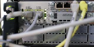网络硬件。正在进行数据传输，彩色指示灯闪烁。光学纤维。线缆已连接到网络设备。服务器的特写。服务器设备碎片。有选择性的重点。