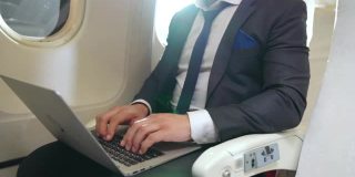 年轻的商人在飞机上使用笔记本电脑