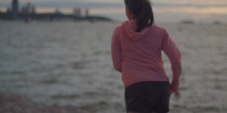 一位穿着运动服慢跑的健身女士在美丽的日落时分看着大海的景色。