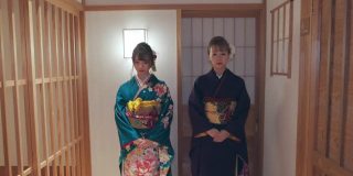 两个穿着Furisode和服的年轻女子一起走在日本旅馆的走廊上