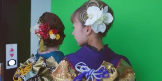 身着Furisode和服的年轻女子在“Purikura”照片贴纸摊上为“Seijin Shiki”成人礼拍照