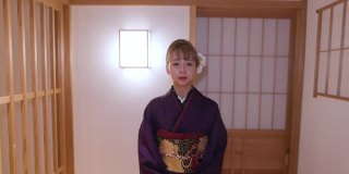穿着Furisode和服的年轻女子走在日本旅馆的走廊上