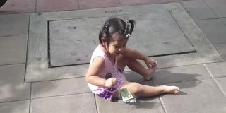 亚洲小女孩在人行道上哭，右手拿着钞票
