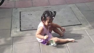 亚洲小女孩在人行道上哭，右手拿着钞票视频素材模板下载
