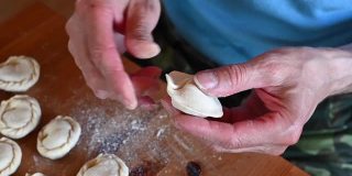 高级男子的手煮和成型的小自制生饺子与肉在厨房桌上。俄罗斯民族传统美食自己动手