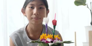 快乐的亚洲女孩花插花(由香蕉叶和花漂浮在河里祈祷和感谢你)一起在家，为晚上的时间做准备。