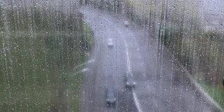 透过湿漉漉的窗户看马路上有雨滴，在雨中有人们的倒影