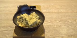 人工将红糖糖浆倒在一碗日本甜点warabi mochi上。