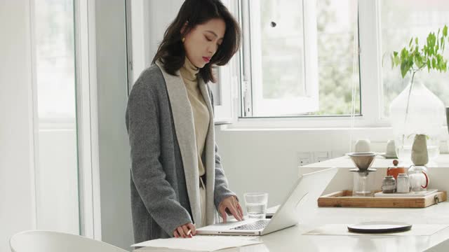 漂亮的亚洲女商人在家里用笔记本电脑工作