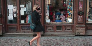戴面具的女人走在老城区的人行道上。