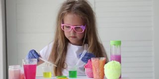 一个戴眼镜的小女孩正在玩自制的粉红色黏液。孩子们用手玩黏液玩具。使粘液。Copyspace。