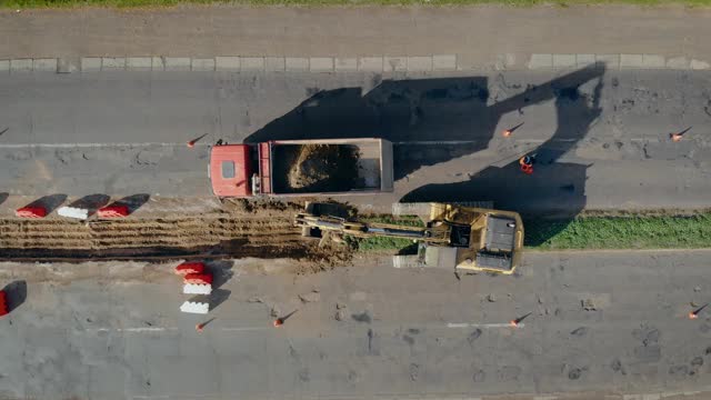 上方航拍拖拉机铲斗正在用地面和石块填满车体。准备地方修复旧路