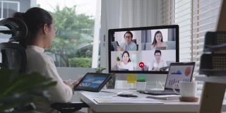 慢速放大女商人在视频会议中谈论销售报告。亚洲团队使用笔记本电脑和平板电脑进行在线视频会议。在家工作，远程工作和在家自我隔离