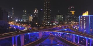 蓝色照明的夜间高架路立交桥和上海城市景观。中国鸟瞰图。无人机向后和向上飞行。远景