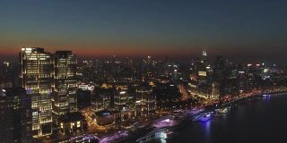 照亮上海城市夜景。浦西和黄浦江。鸟瞰图。无人机向后飞行。