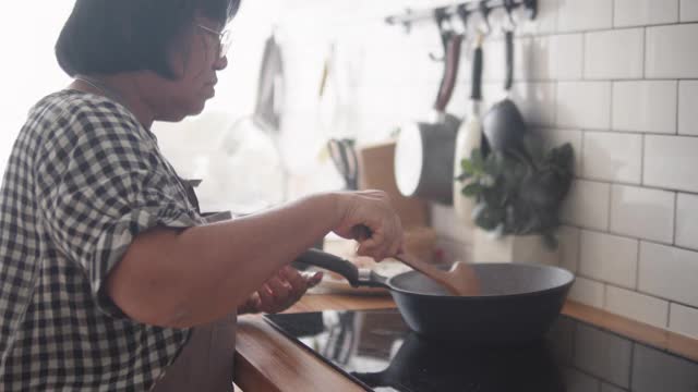 亚洲高级妇女准备食物。