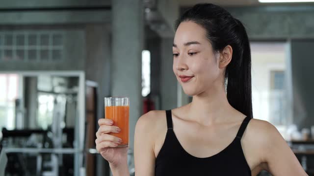 亚洲美女在健身房喝果汁的肖像。