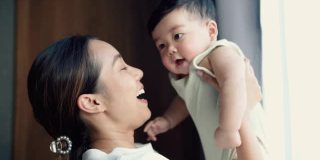 年轻的亚洲母亲抱着她可爱的儿子