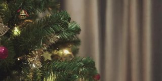 一个面目全非的女人把金色的铃铛挂在圣诞树上装饰