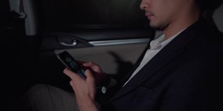 一个在豪华轿车后座上使用智能手机的商人