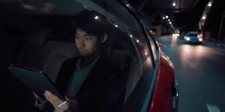 疲惫的商人在回家的路上在车里用平板电脑玩社交媒体