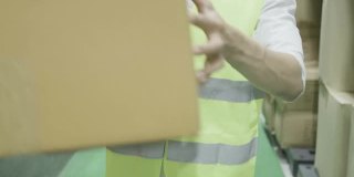 员工男性仓库专业工人戴着防护面罩、安全帽和套装绿色反光安全服在物流中心工厂的货架上堆放库存工作。