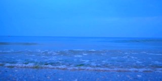 海浪在夜晚的海滩上溅起水花。慢动作效果。