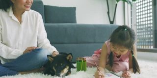 亚洲母亲和女儿画绘画与他们的狗。家庭室内休息。