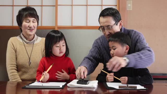 亚洲的祖父母和孙辈在练习书法