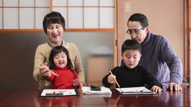 亚洲的祖父母和孙辈在练习书法