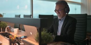 留着胡子的亚洲华人成熟商人，在办公室用笔记本电脑给客户打字和回复电子邮件，与客户进行视频通话