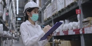 仓库工人或亚洲妇女快乐劳动佩戴医用口罩，防止冠状病毒和PM2.5粉尘。在运输行业工作时要戴安全帽以保护自己。概念的关键员工