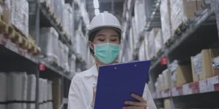 仓库工人或亚洲妇女快乐劳动佩戴医用口罩，防止冠状病毒和PM2.5粉尘。在运输行业工作时要戴安全帽以保护自己。概念的关键员工
