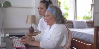 亚洲高级妇女和女儿视频会议在家里的电脑