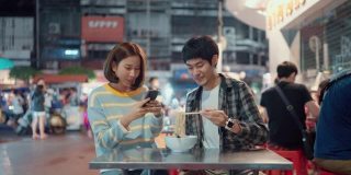 一对年轻夫妇正在享受街边小吃，并把照片发到社交媒体上