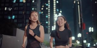 两个女运动员晚上在城市的街道上练习跑步。