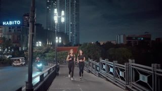 成功的女运动员晚上在城市的街道上练习跑步。视频素材模板下载