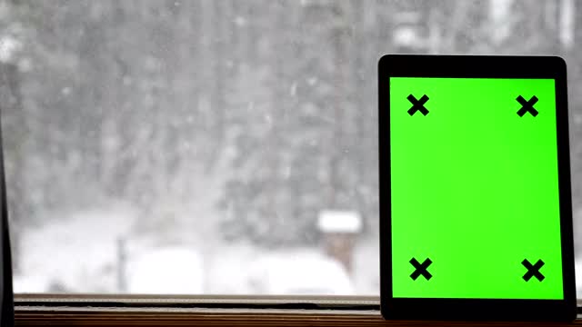 在下雪时手持绿色屏幕的数字平板电脑