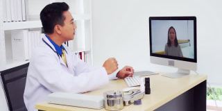 身穿白大褂的男性医疗助理用笔记本电脑视频呼叫远方的病人。医生与客户使用虚拟聊天电脑应用程序。