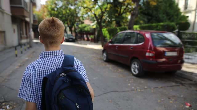 男孩拿着书包放学回家