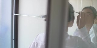 摄影女子进入浴室，用反射镜看脸的场景。