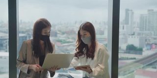 两个亚洲商业女性使用笔记本电脑互相建议