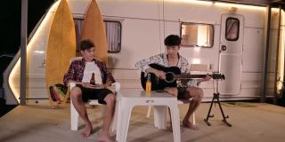 年轻的亚洲朋友喜欢在度假的露营车里闲逛和弹吉他