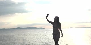 美丽的亚洲女人在一个游泳衣跑和拍一个快乐的照片自己在海滩上