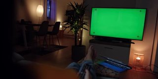 一个陌生的女人在彩色键绿色屏幕的电视上浏览频道