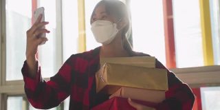 亚洲女人用手机拍照，戴着口罩拿着礼物盒
