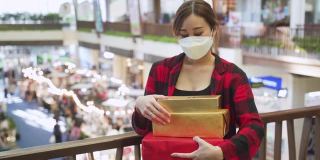 亚洲女人用手机戴着口罩拿着礼物盒