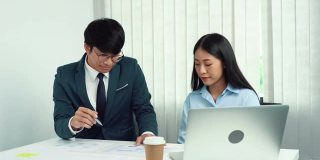 亚洲经理正在向员工解释手提电脑上的信息。