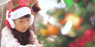 小女孩在圣诞节用装饰品装饰圣诞树